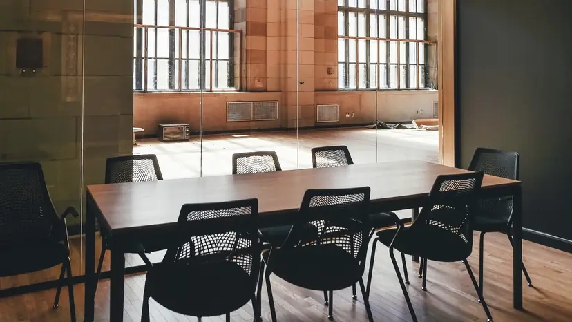 Sala de reuniones vacía con mesa larga y ventanales