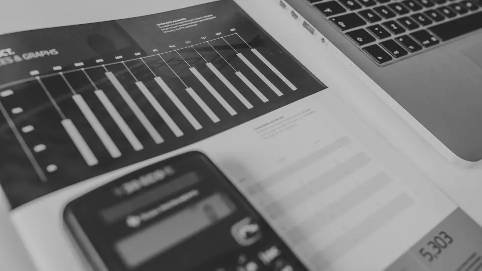 Calculadora y planilla con gráficos de barras sobre un escritorio