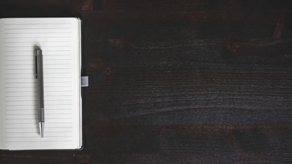 Libreta y lapicera sobre una superficie oscura, el registro de contactos antes de un CRM
